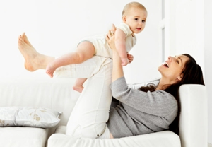 woman smiling and playing with her baby, enjoying her white sofa, baby safe and sanitised upholstery cleaning makes you feel relaxed